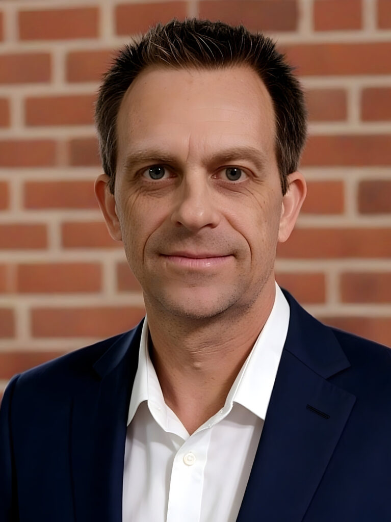 Neil Monroe headshot with a red brick background